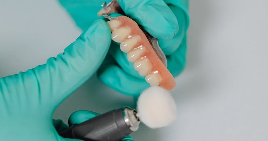 a close up shot of a person polishing a denture